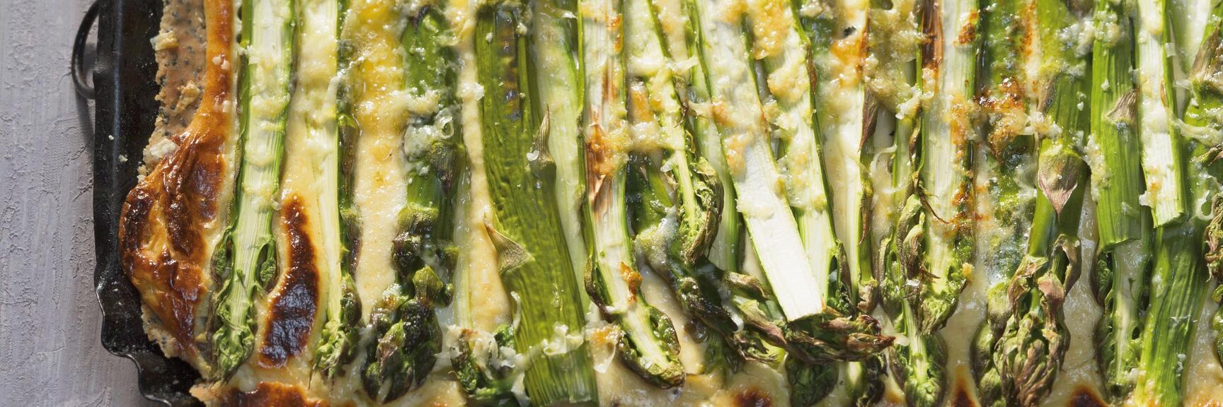 Baked asparagus quiche in rectangular form with antique knife on grey background.