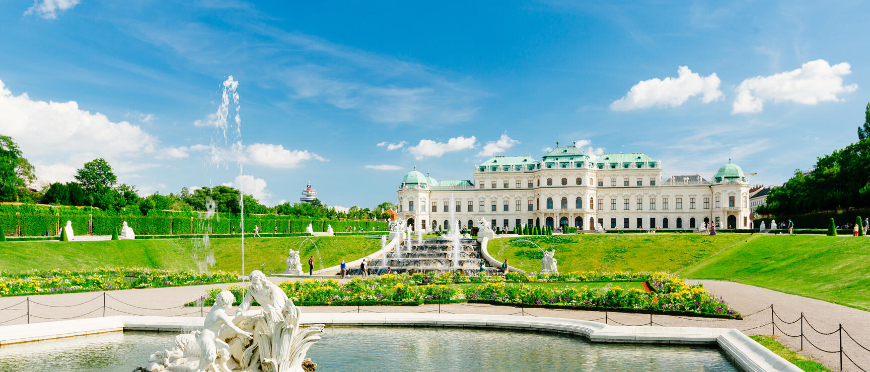 Belvedere Palace Vienna with Baroque garden, fountain, figure group in water basin, blue summer sky.