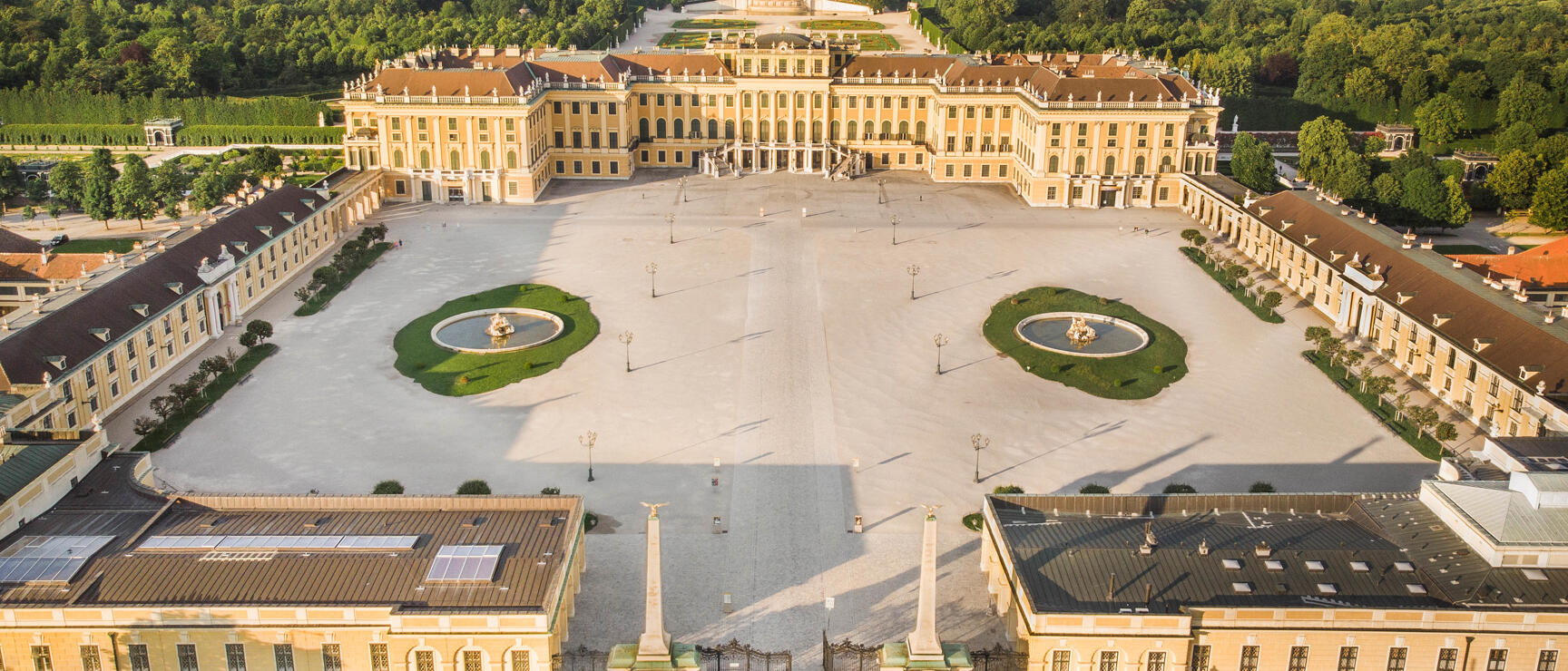 Aerial view of Schönbrunn Palace in Vienna with honour court, two fountains and Gloriette in background.