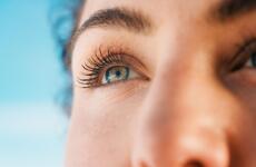 A close-up of an eye reflecting the winter mountain landscape. The subtle glints of light and the focused gaze convey a sense of calm, a connection to nature, and the special atmosphere of a clear winter day in Austria.