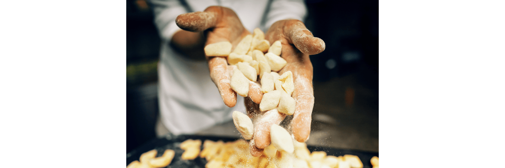 Flour-dusted hands holding fresh gnocchi with pieces falling, cooked gnocchi visible in foreground.