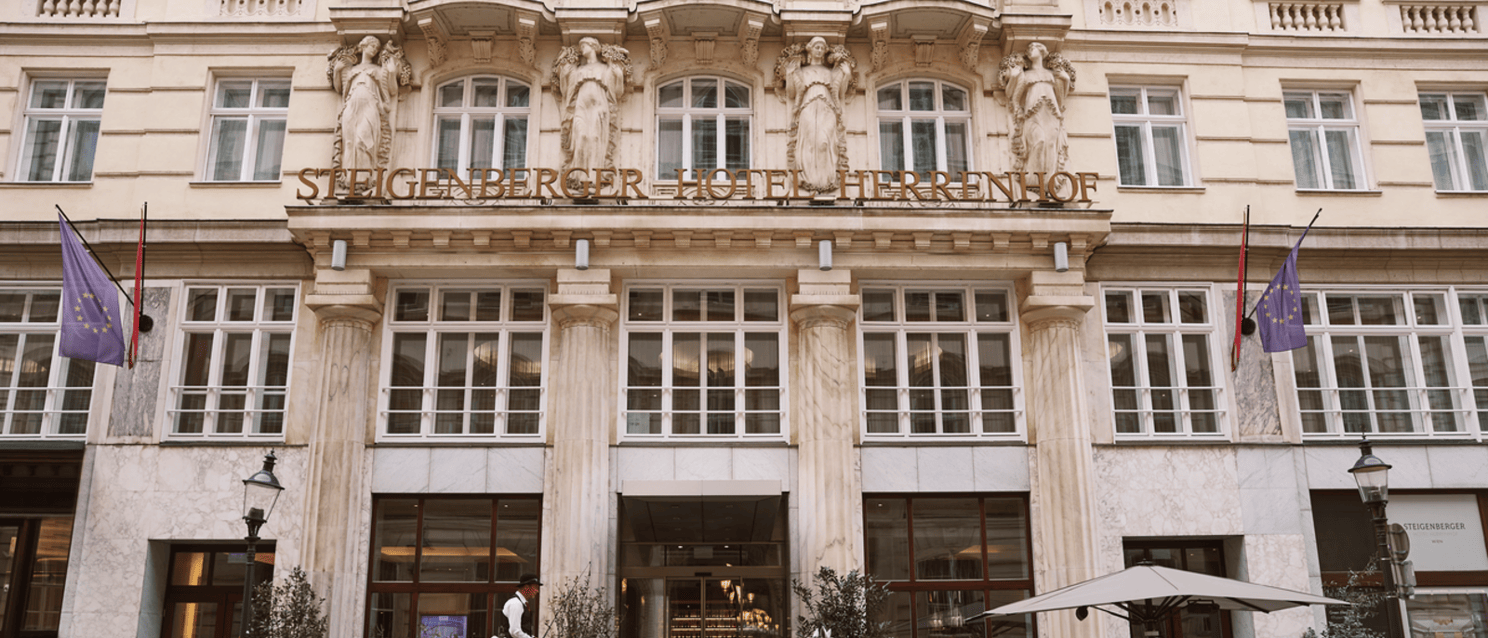 Fiaker with white horse in front of Steigenberger Hotel Herrenhof in Vienna, Gründerzeit facade with statues.