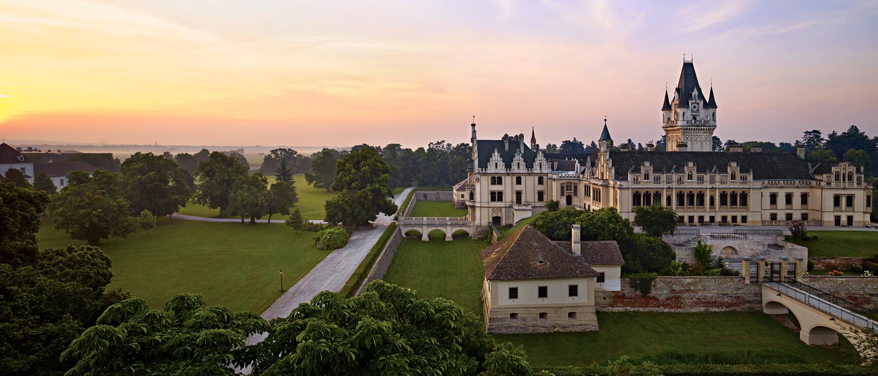 Schloss Grafenegg at sunset surrounded by parkland with bridge and trees, Lower Austria.