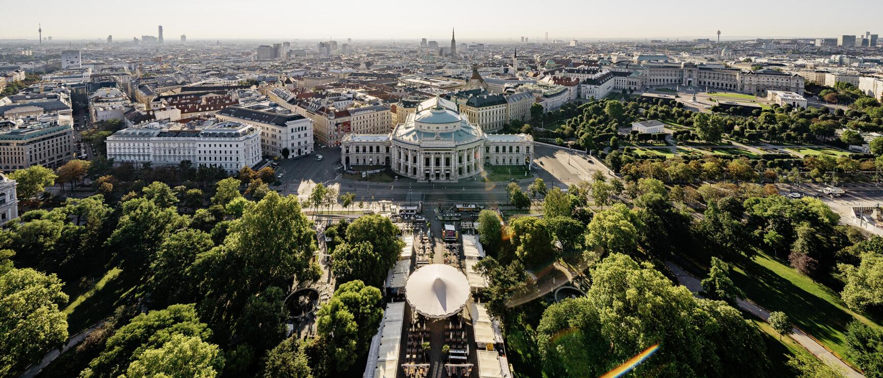 Luftaufnahme Wien mit Burgtheater, Rathauspark und Stadtpanorama bei sonnigem Wetter.