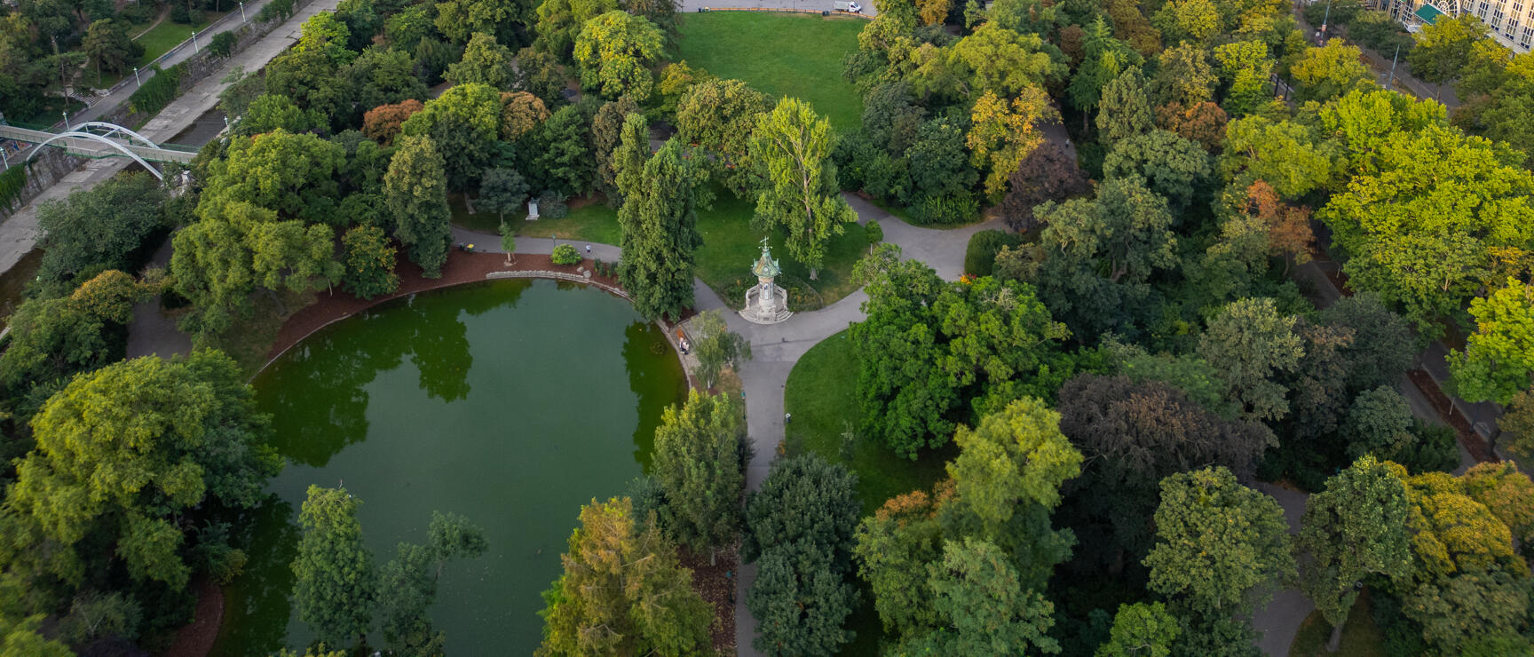 Aerial view of Vienna's Volksgarten with pond, paths, pavilion and fin-de-siècle buildings in background.