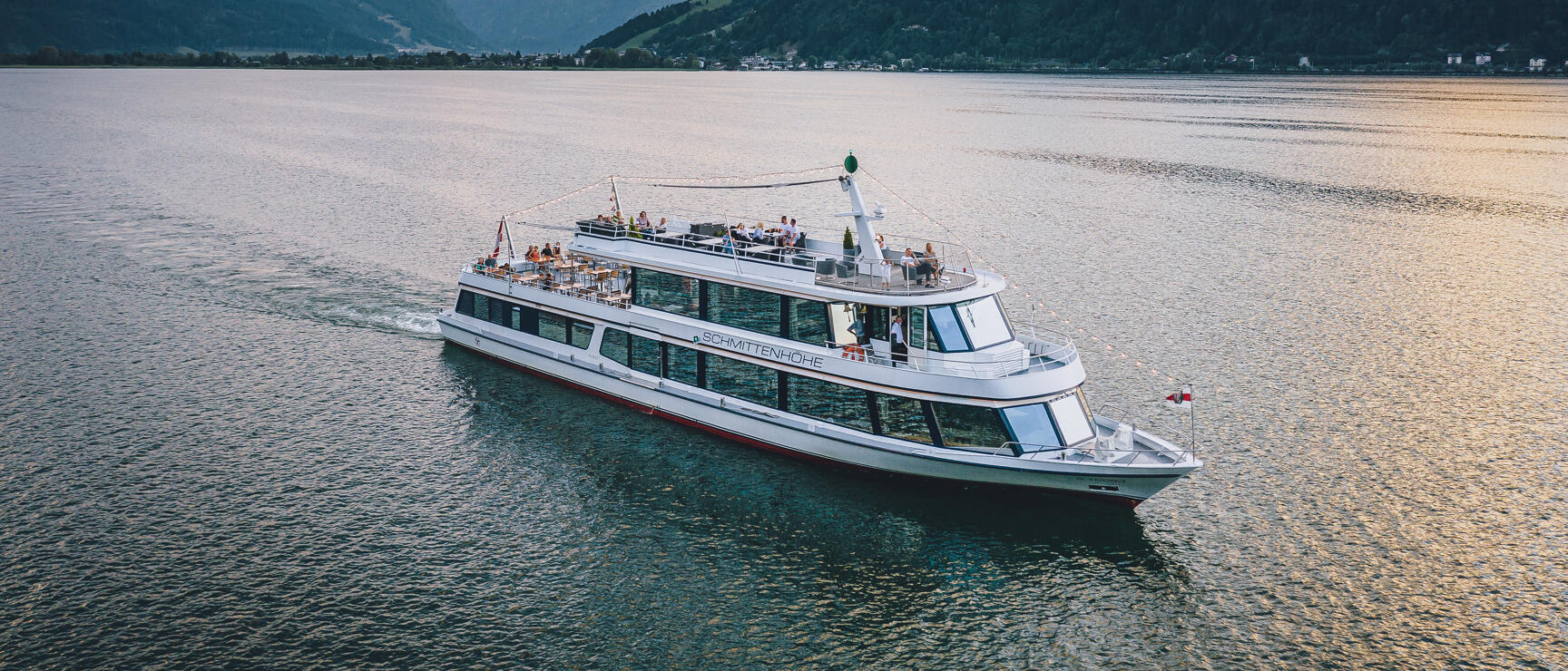 Passenger ship 'Schmittenhöhe' on Zeller See at sunset, Alps in background.
