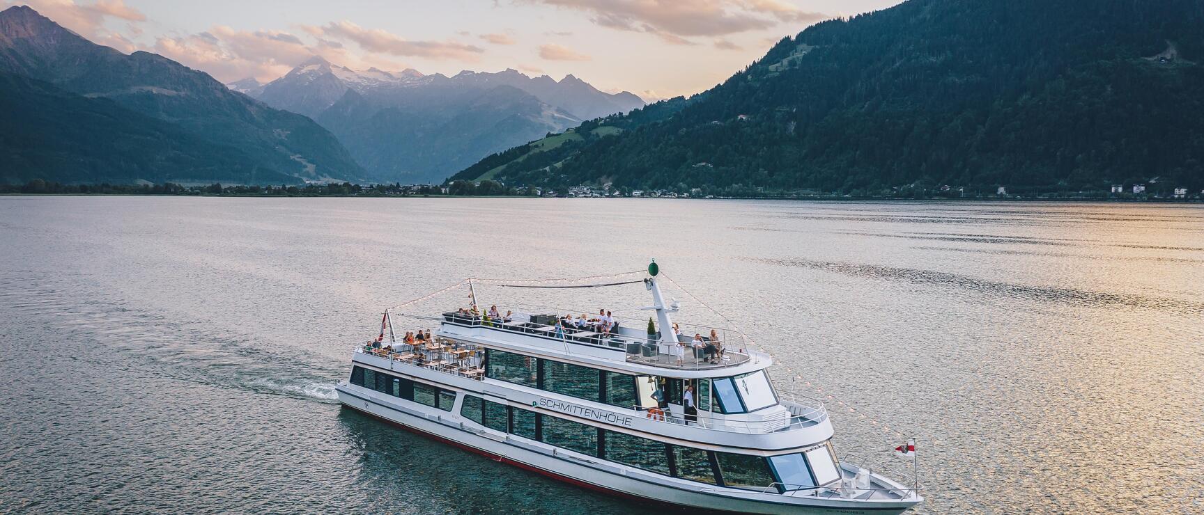 Passenger ship 'Schmittenhöhe' on Zeller See at sunset, Alps in background.