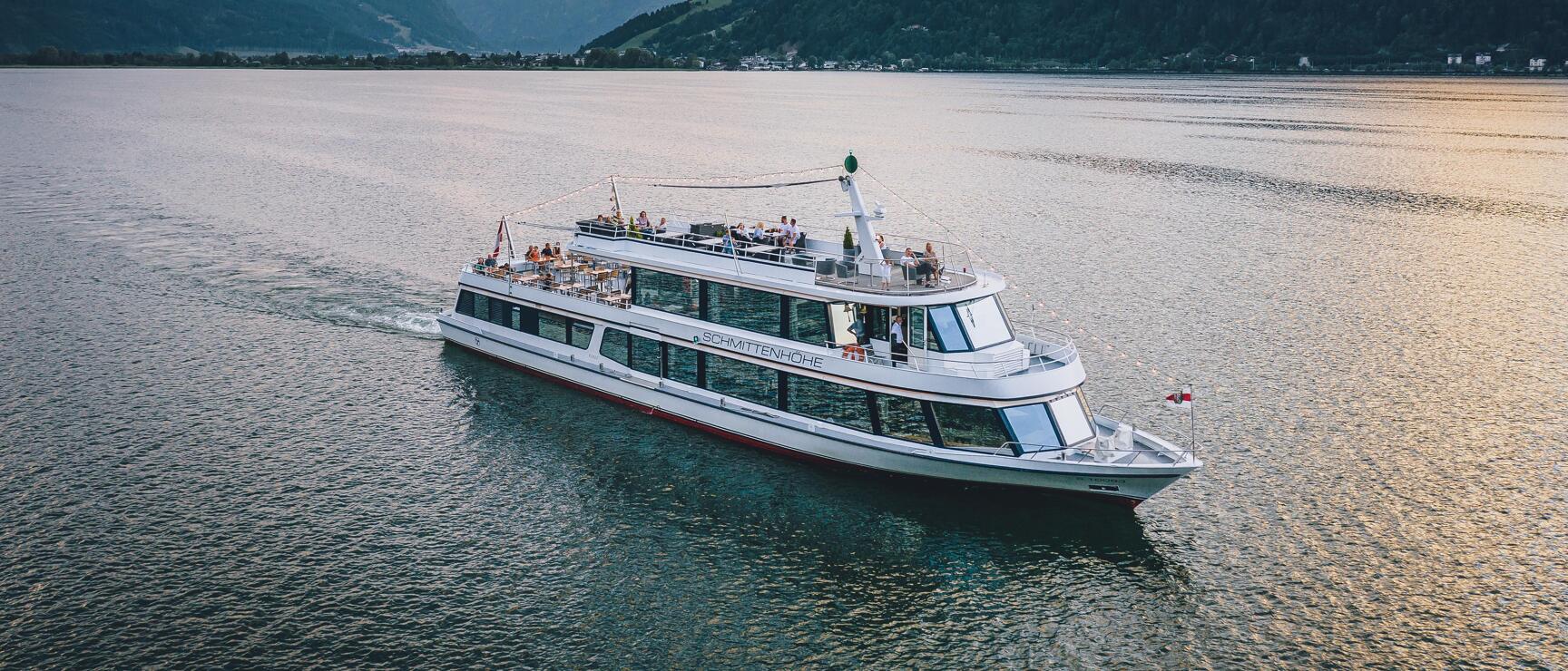 Passenger ship 'Schmittenhöhe' on Zeller See at sunset, Alps in background.