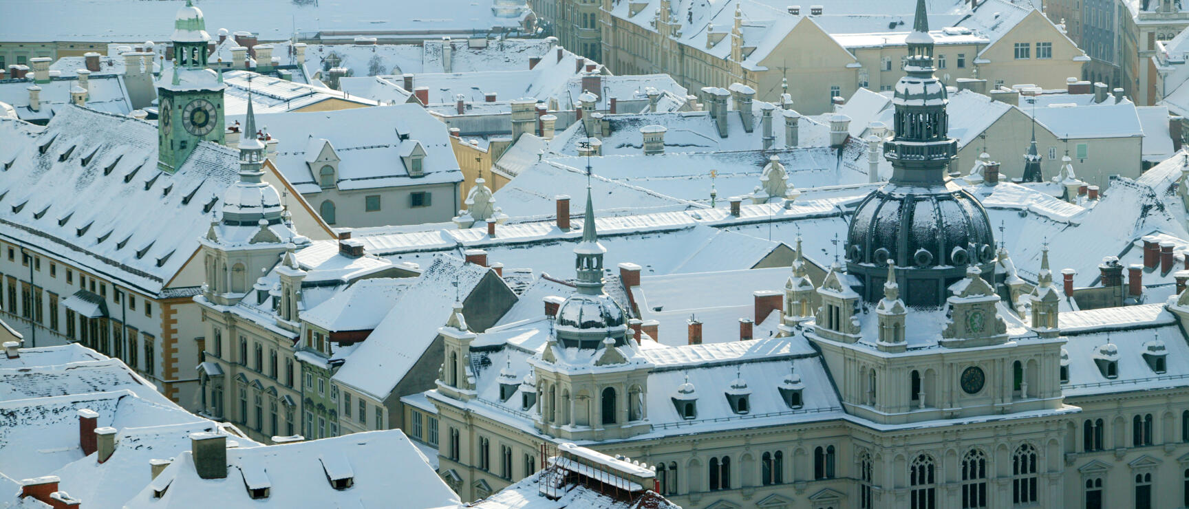 Snow-covered old town of Graz from bird's-eye view, town hall with dome tower in foreground.