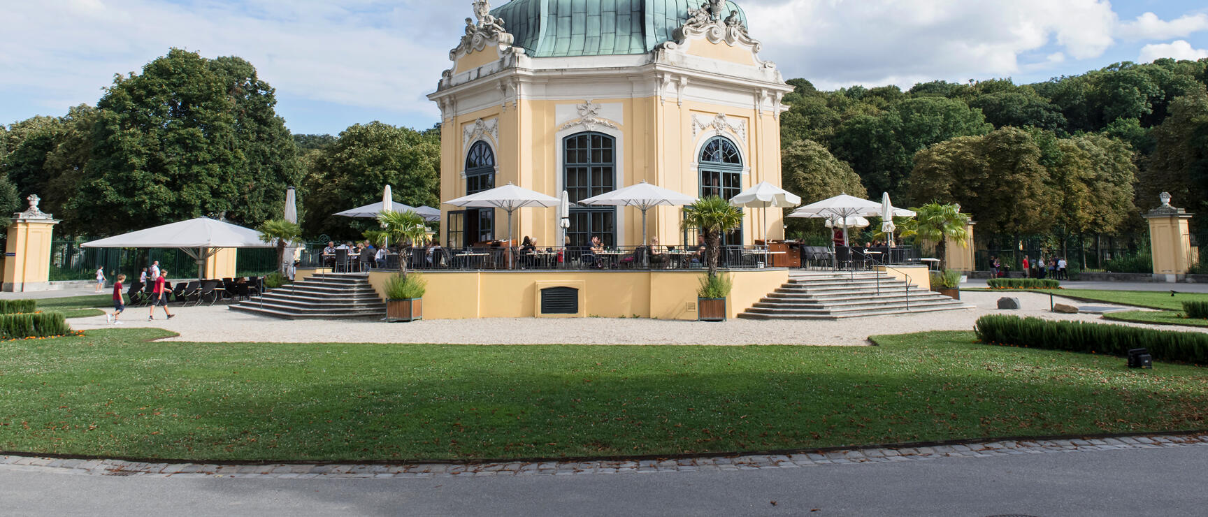 Imperial Pavilion in Schönbrunn Zoo with terrace café, white umbrellas and green space, Vienna.
