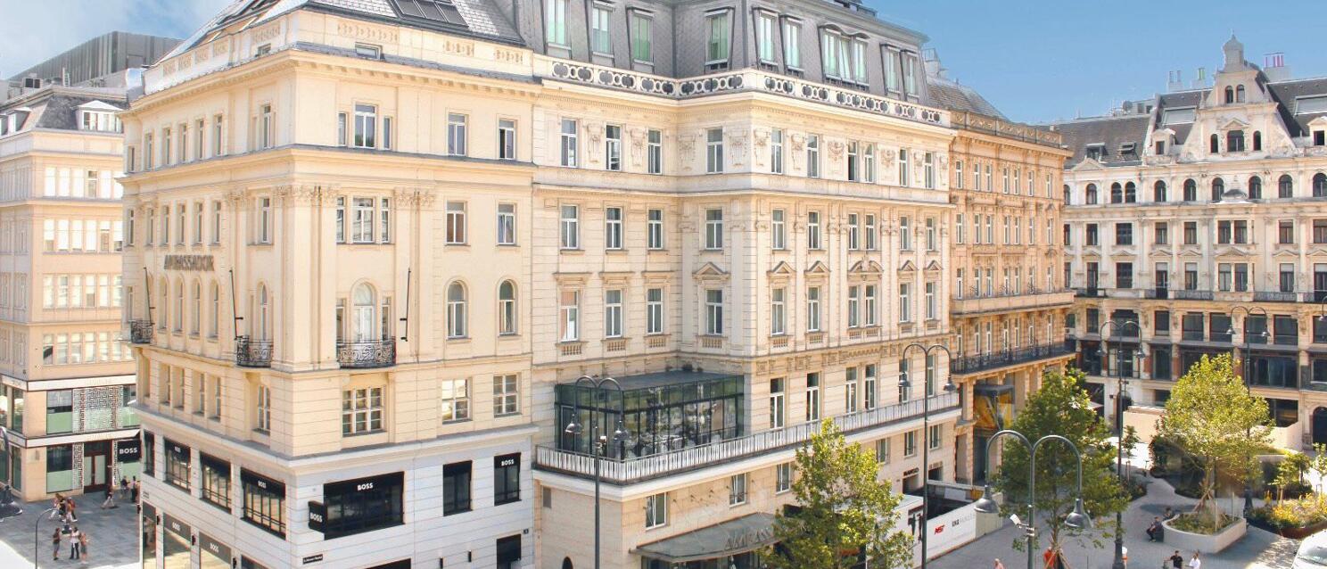 Gründerzeit facade of Hotel Ambassador on Kärntner Straße in Vienna, pedestrians and shops on ground floor.