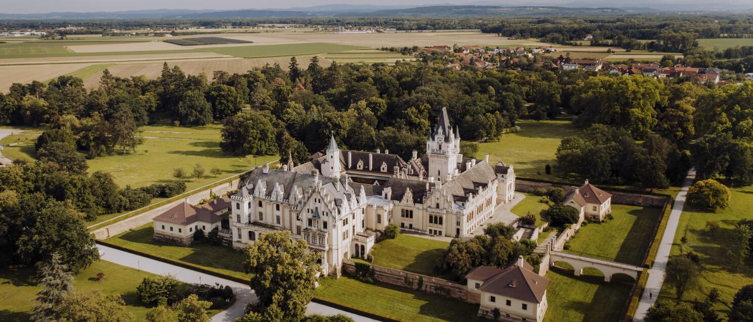 Luftaufnahme von Schloss Grafenegg mit Parkanlagen, umgeben von Feldern und Wäldern, Niederösterreich.