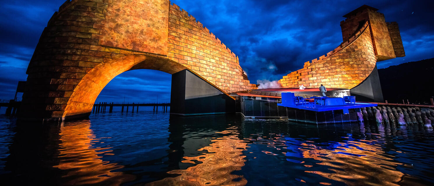 Illuminated stage setting of a lake stage at night, water reflection, cloudy sky, Bregenz.