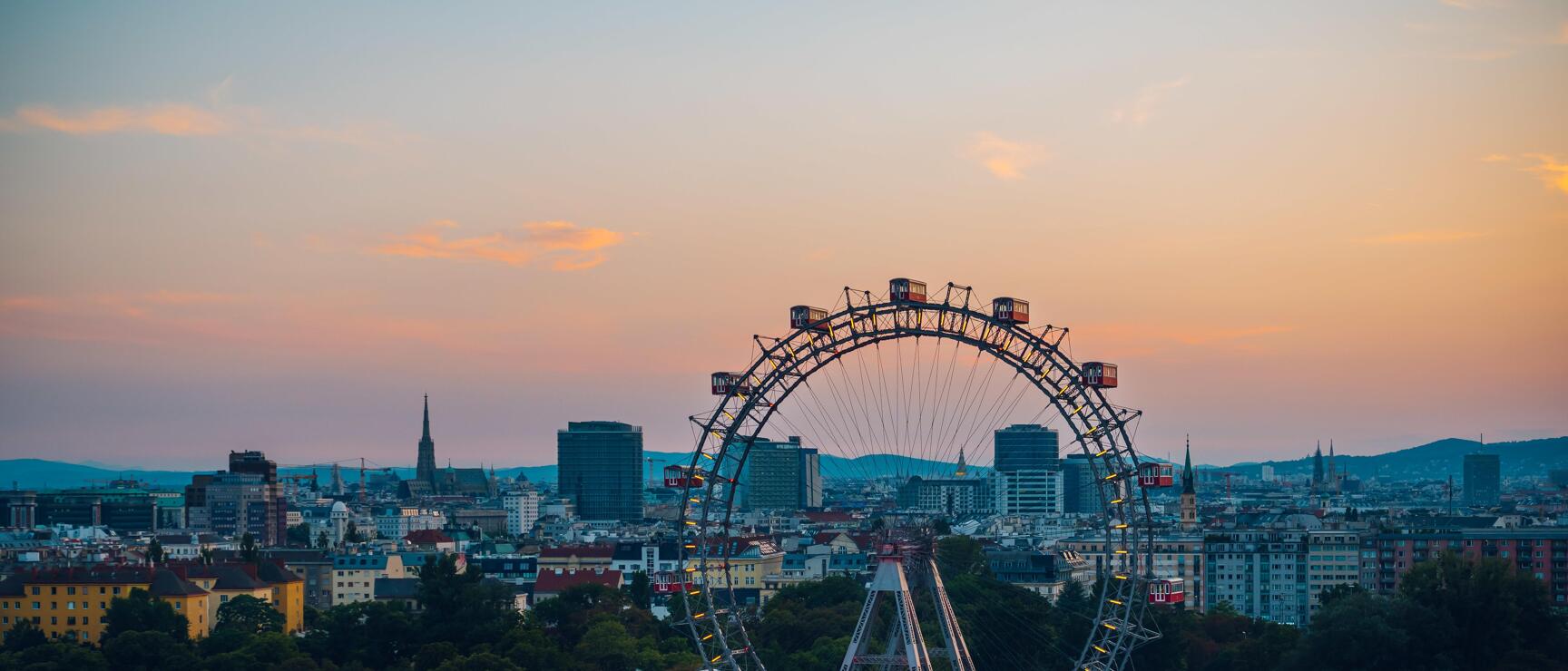 Vienna Ferris Wheel in Prater at sunset, Vienna city panorama in background.