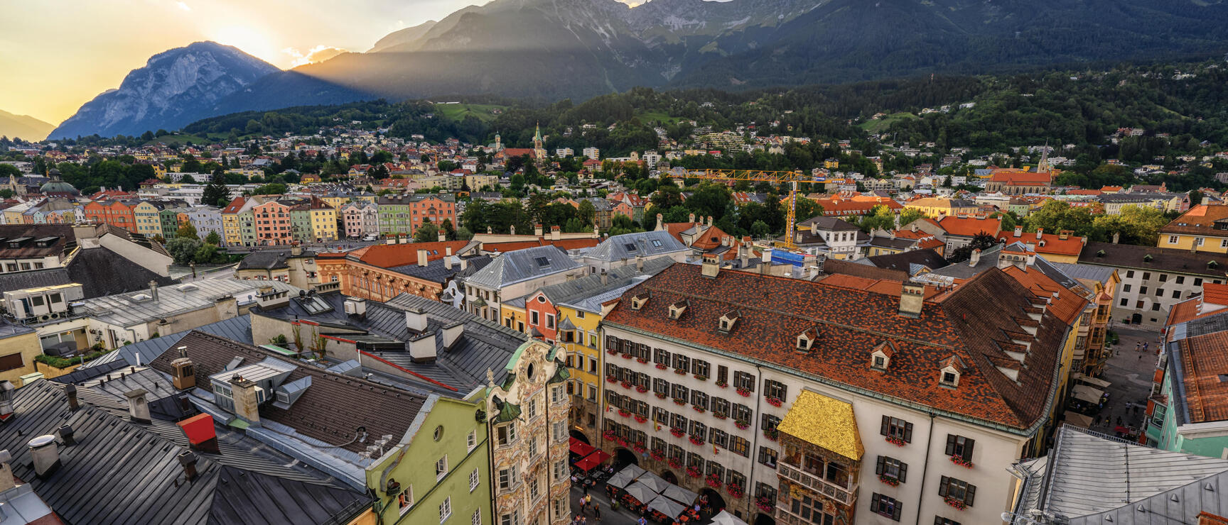 Aerial view of Innsbruck's old town with Golden Roof, colourful buildings and Karwendel mountains in evening light.