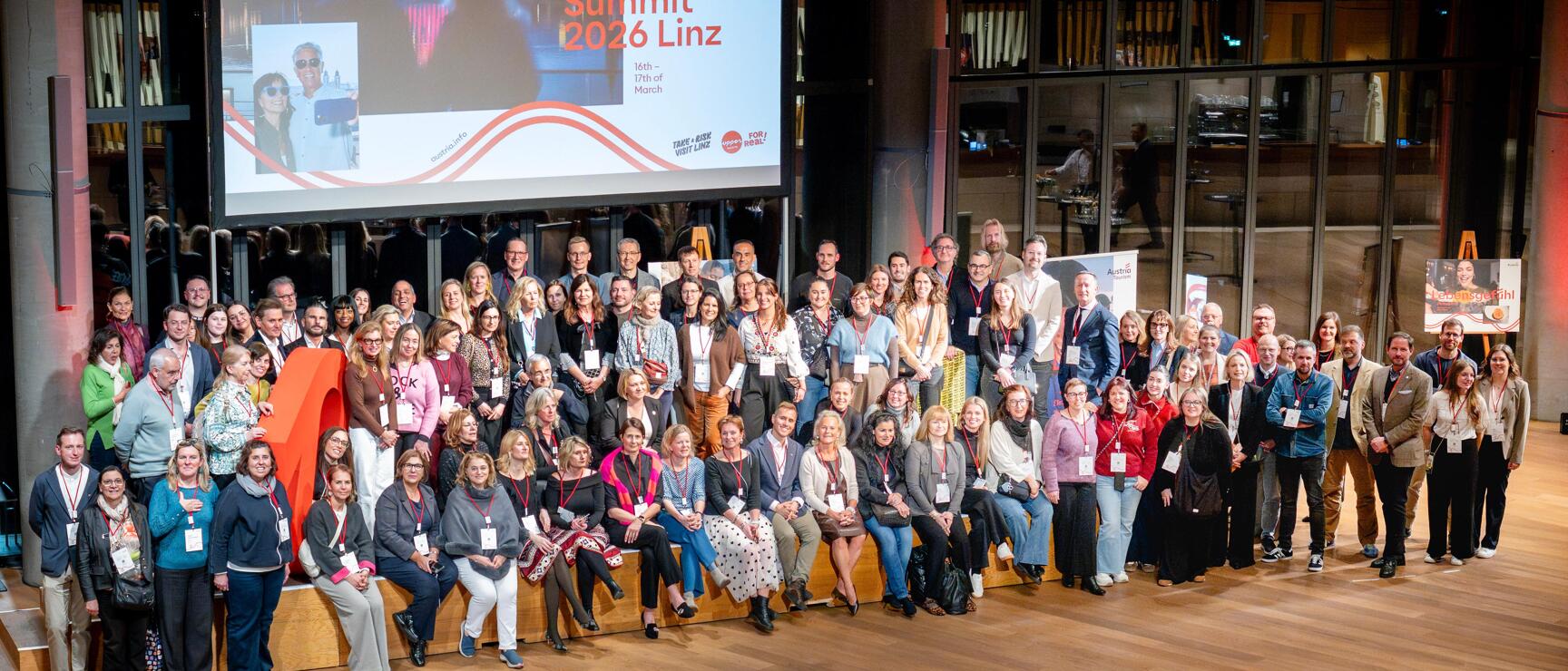 Große Gruppe von Teilnehmer:innen posiert vor einer Bühne beim Travel Trade Summit.