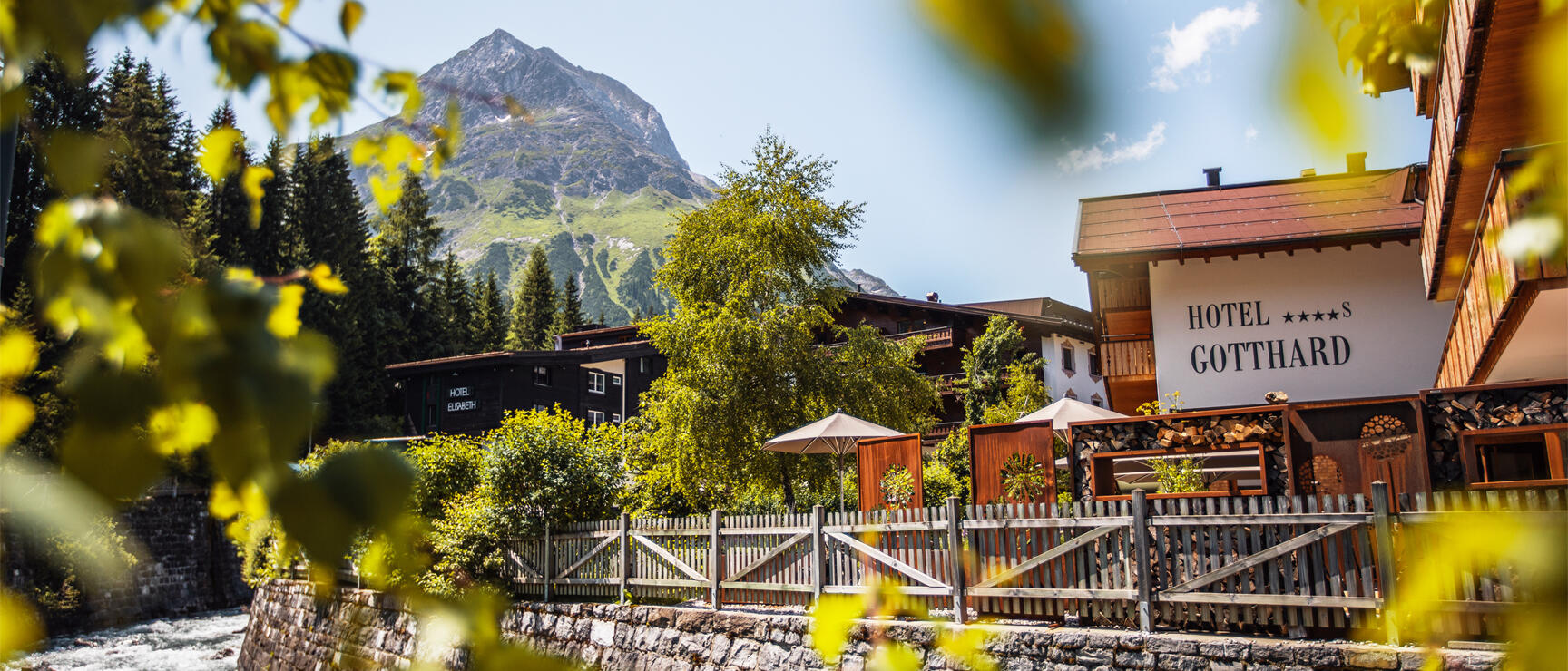 Hotel Gotthard and Hotel Elisabeth by a stream, mountain peak in the background, Lech am Arlberg.