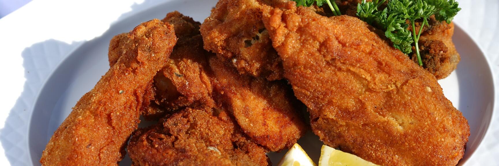Gebratene Schnitzel auf weißem Teller, garniert mit Zitronenspalten und frischer Petersilie.
