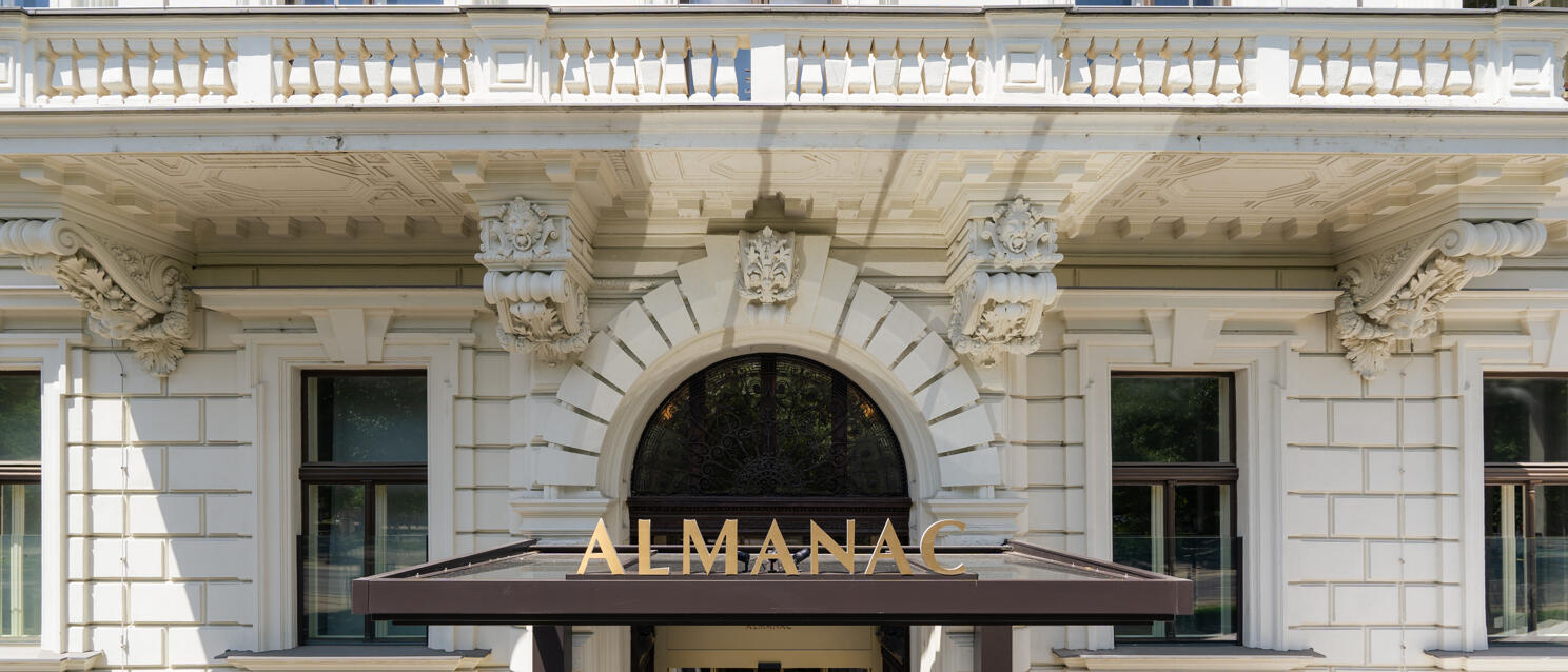 Entrance of Hotel Almanac Vienna, Gründerzeit façade with rounded arch, canopy with golden lettering.