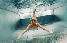 Woman in bikini diving into stainless steel pool, underwater shot from below.