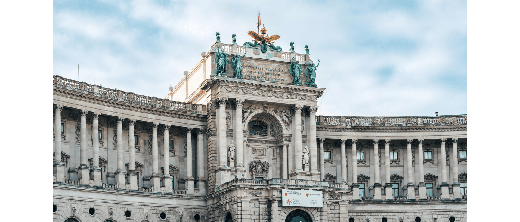 Neue Burg of Vienna Hofburg with bronze statues, golden eagle and national library signage.