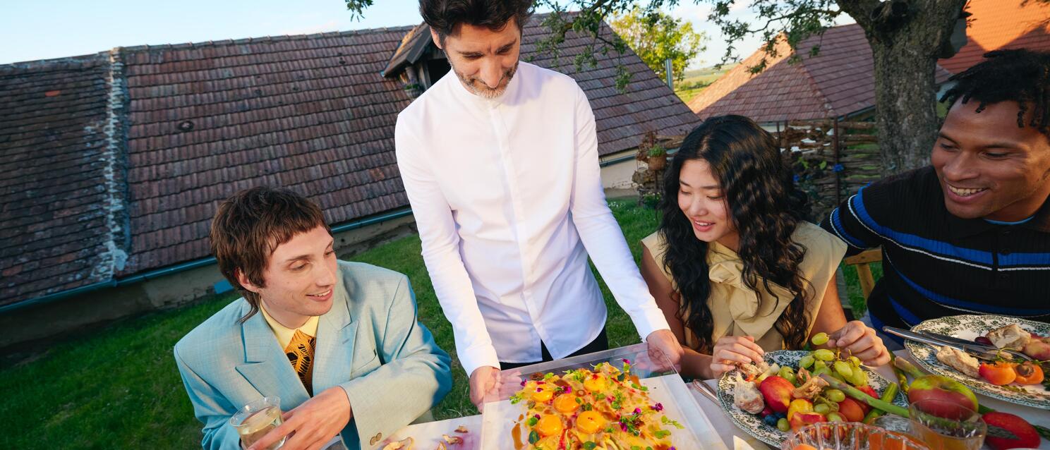 Küchenchef Paul Ivić, Restaurant Tian, bewirtet Gäste an einer gedeckten Tafel unter einem Apfelbaum vor einem Presshaus in der Kellergasse im Weinviertel.