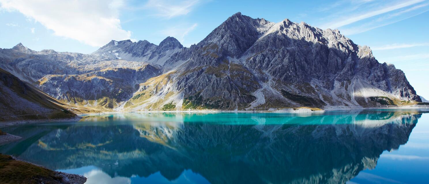Turquoise blue mountain lake with reflection of rocky peaks, Lünersee, Vorarlberg.