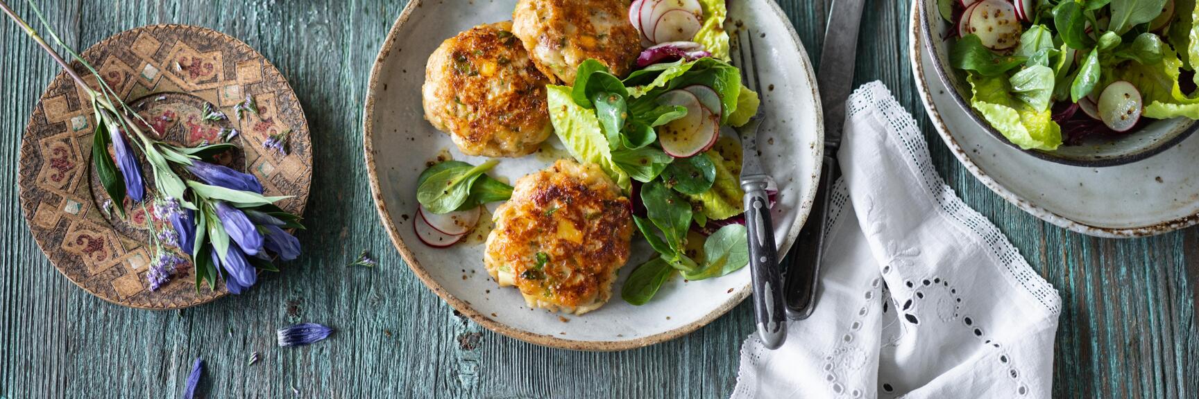 Fried meatballs with salad and radishes on rustic table, salad bowl, salt, pepper and candlestick nearby