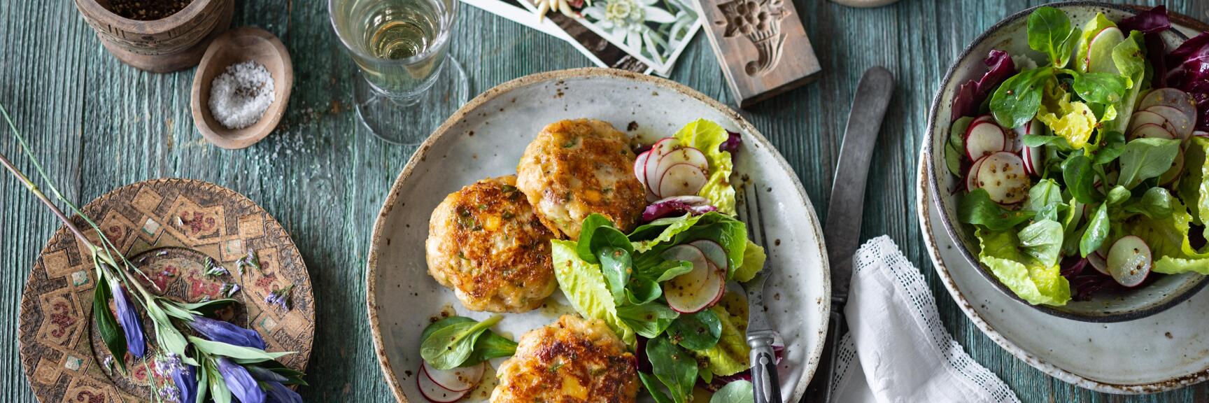Fried meatballs with salad and radishes on rustic table, salad bowl, salt, pepper and candlestick nearby