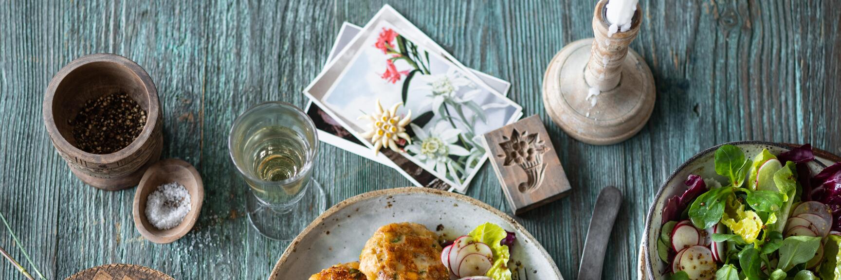 Fried meatballs with salad and radishes on rustic table, salad bowl, salt, pepper and candlestick nearby