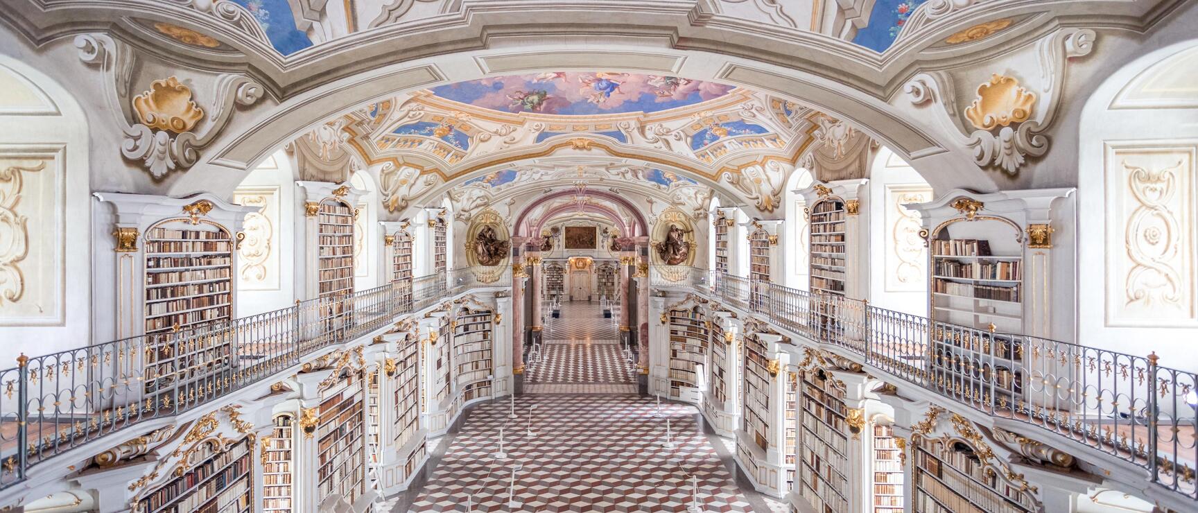 Barocke Bibliothek des Stifts Admont: mehrstöckige Bücherregale, Freskendecke, Marmorboden in Rot-Weiß.