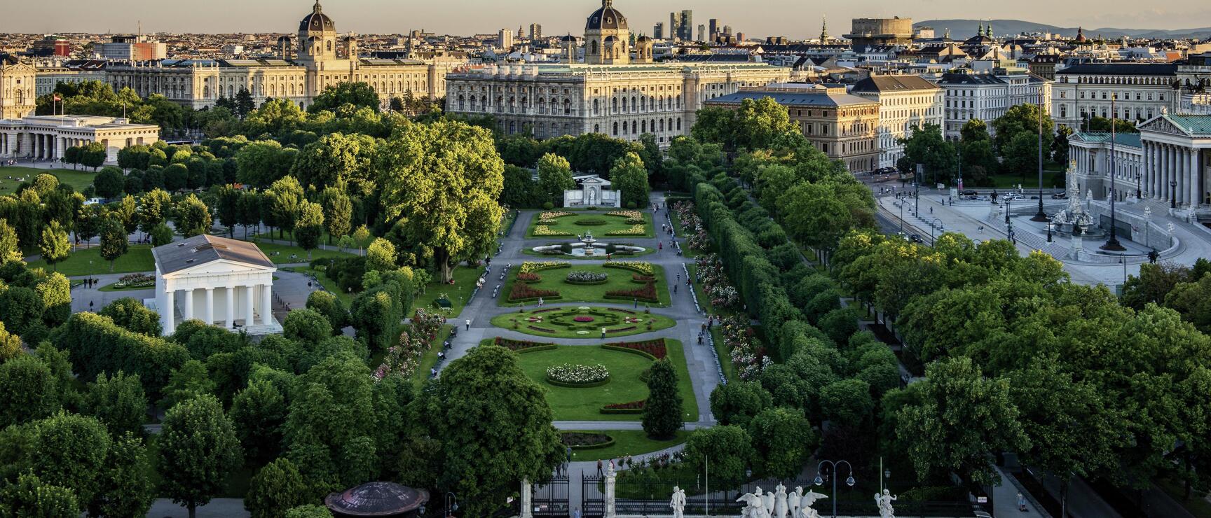 Aerial view of Vienna's Volksgarten with flower beds, Museum of Art History and Parliament in the background.