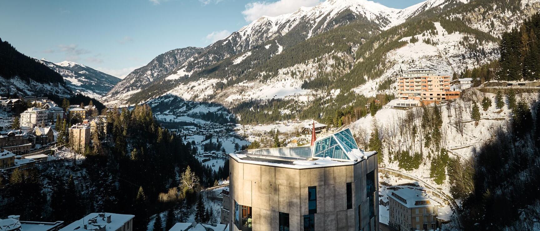 Winter panorama of Bad Gastein with modern rotunda, snow-covered mountains and village in the valley.