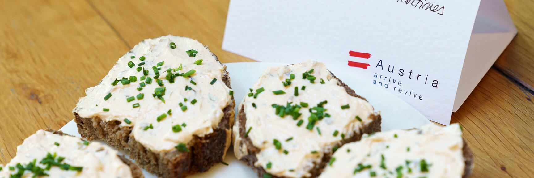 Bread slices with Liptauer spread and chives on plate, with labeled card beside.