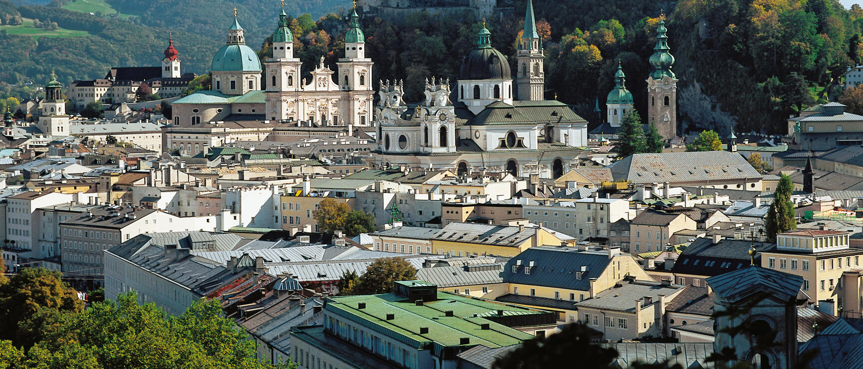 Panoramic view of Salzburg's old town with cathedral, church towers and Hohensalzburg fortress on the cliff above.