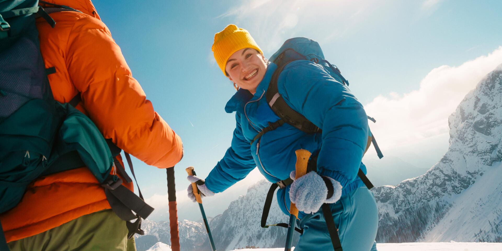 Two people snowshoeing in the Austrian mountains. Under the bright winter sun, they enjoy the snow-covered landscape, the crisp mountain air, and moments together filled with lightheartedness and joie de vivre.