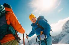 Zwei Personen beim Schneeschuhwandern in den österreichischen Bergen. Unter strahlender Wintersonne genießen sie die verschneite Landschaft, die klare Bergluft und gemeinsame Momente voller Leichtigkeit und Lebensfreude.