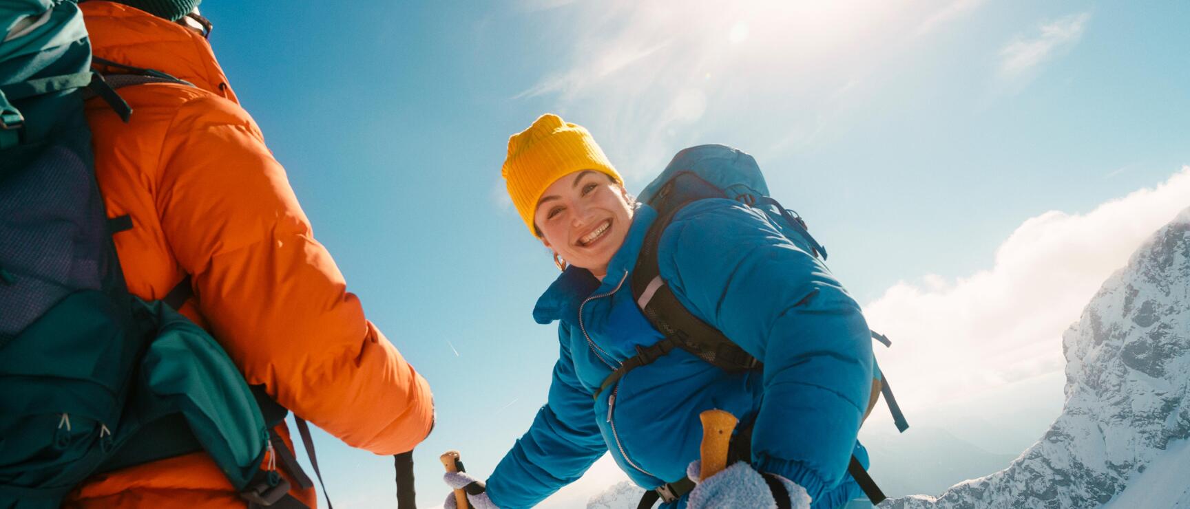 Two people snowshoeing in the Austrian mountains. Under the bright winter sun, they enjoy the snow-covered landscape, the crisp mountain air, and moments together filled with lightheartedness and joie de vivre.
