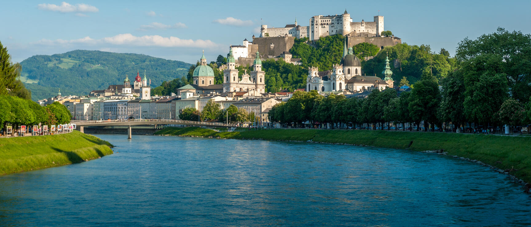 Salzburg old town with cathedral, Hohensalzburg Fortress on cliff and Salzach river in foreground.