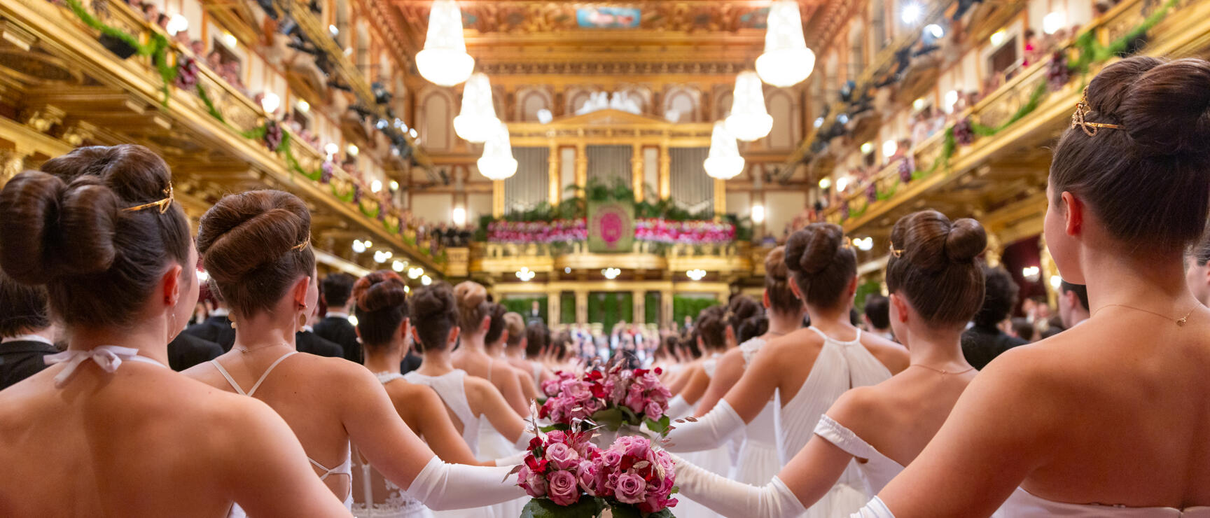 Debütantinnen in weißen Kleidern mit Rosenstrauß im Goldenen Saal des Wiener Musikvereins.