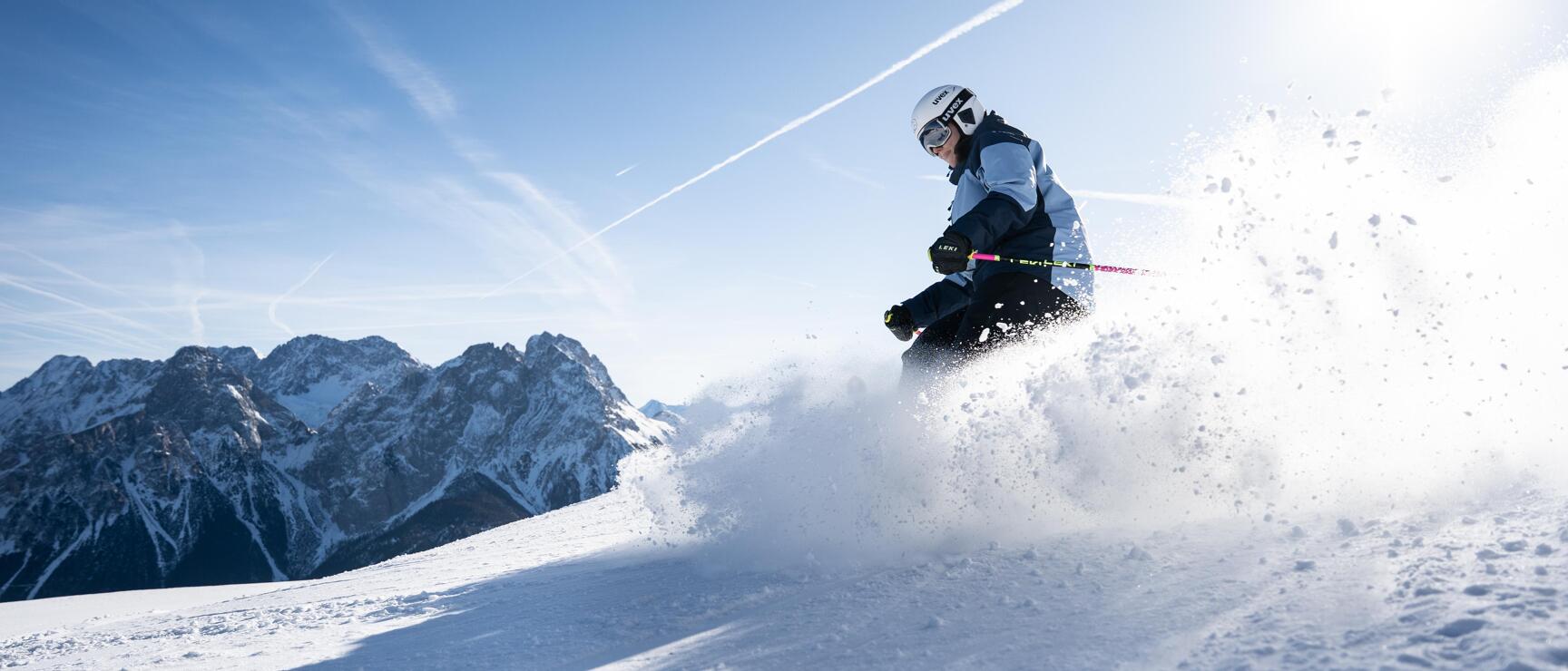 A skier on a groomed slope in the Grubigstein Lermoos ski area in the Tyrolean Zugspitz Arena, set against a wintry Alpine backdrop