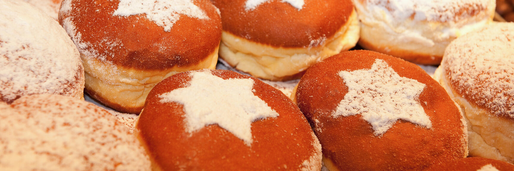 Multiple donuts with powdered sugar star pattern on surface, close-up.