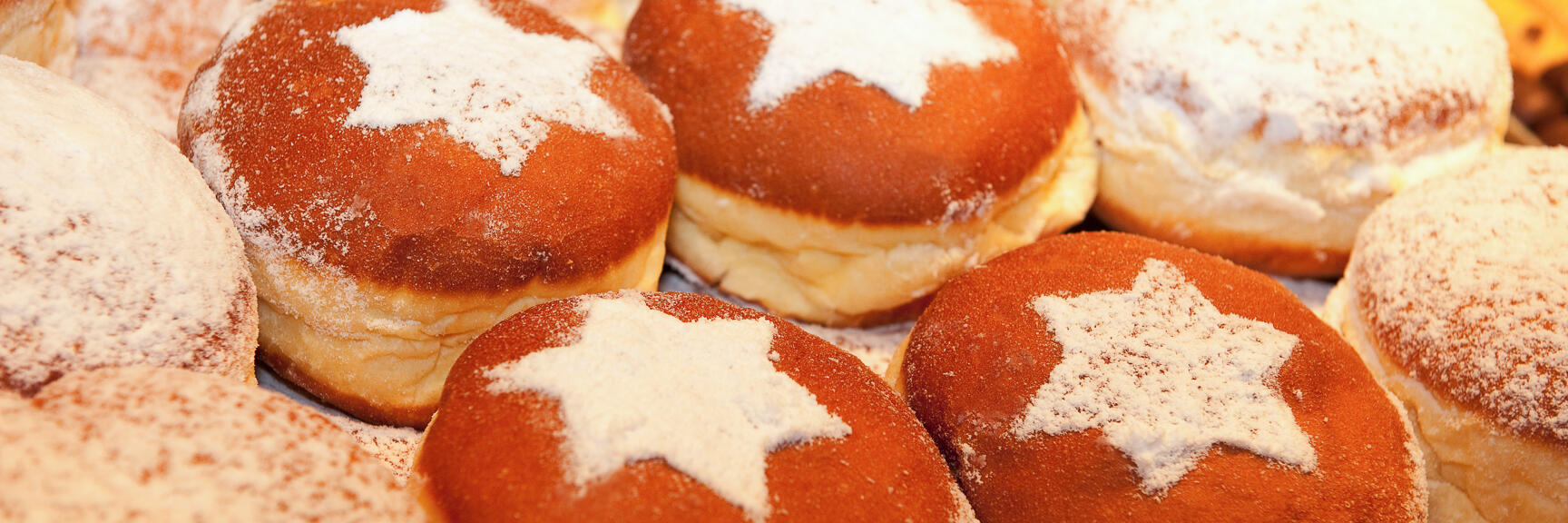 Multiple donuts with powdered sugar star pattern on surface, close-up.