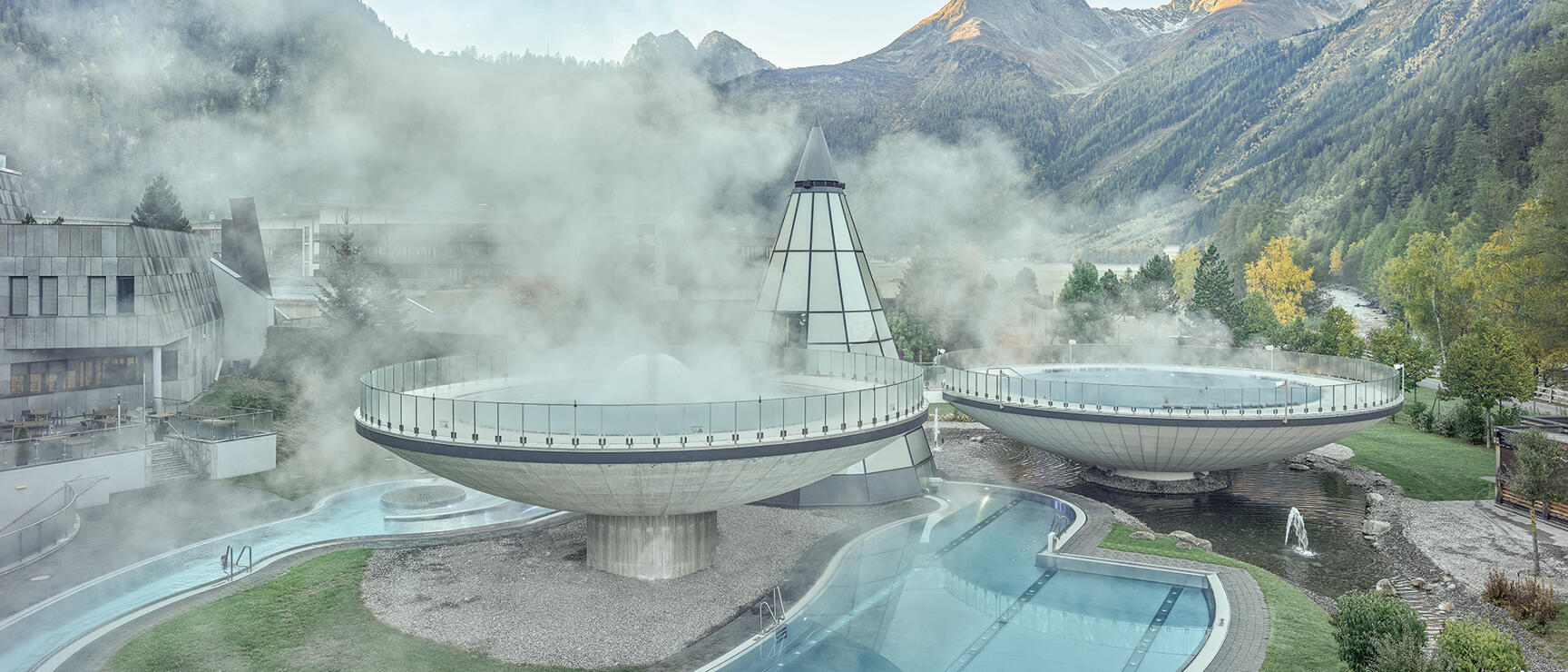 Aqua Dome Tirol: two disc-shaped thermal pools with steam, outdoor pools and mountain panorama in the background.