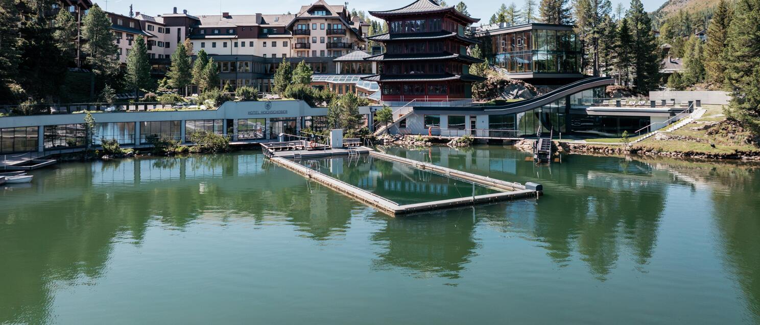 Außenansicht des Hotels Hochschober am See auf der Turracher Höhe, im Vordergrund eine Plattform im Wasser
