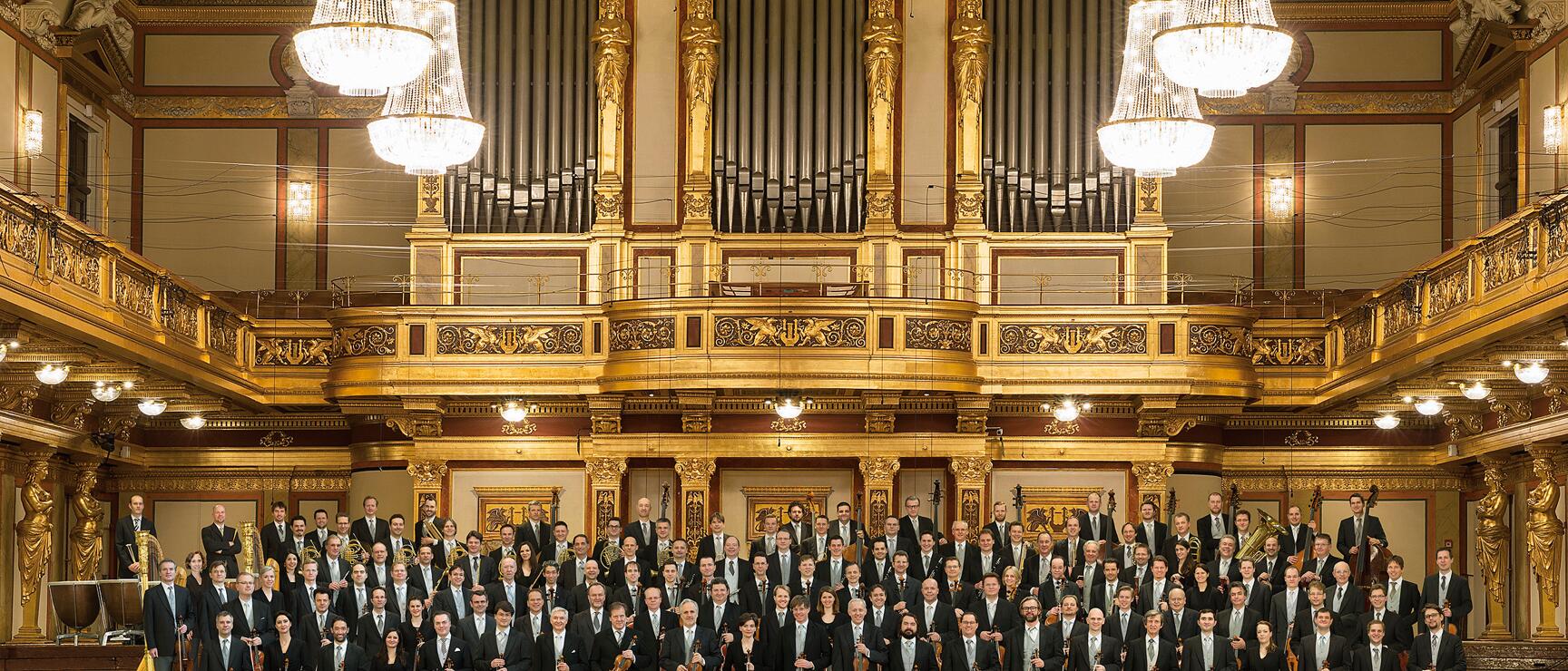 Large orchestra with string instruments in the Golden Hall of the Vienna Music Association, organ in the background.