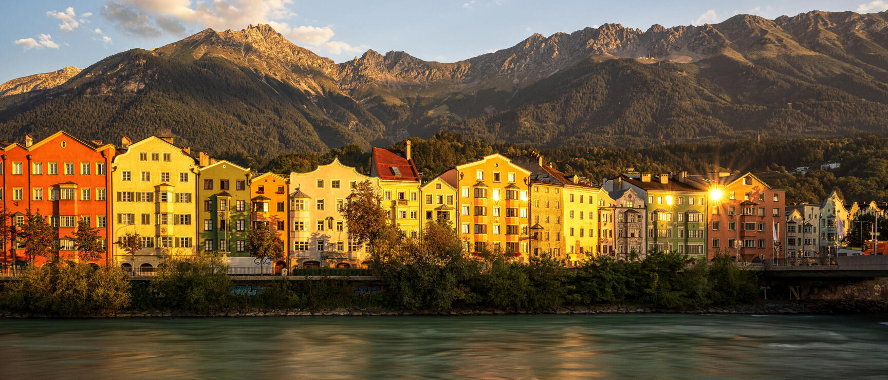 Colourful row of houses along the Inn in Innsbruck in evening light, Nordkette in background.