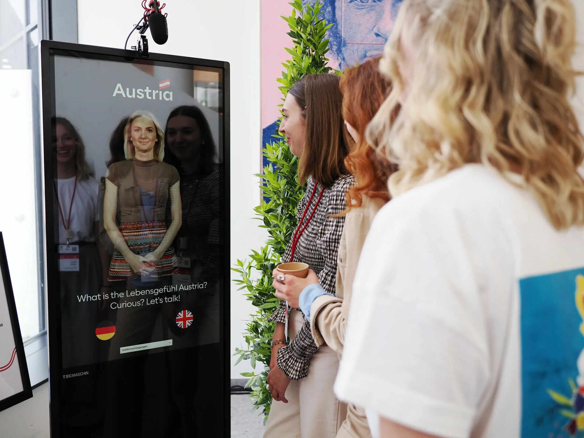 Besucher stehen vor interaktivem Display mit virtuellem Avatar.
