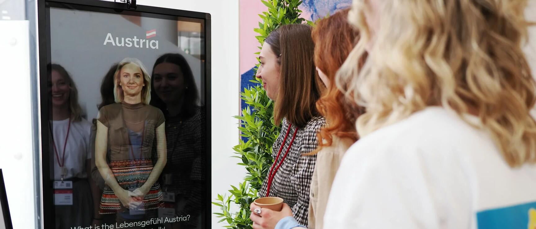 Besucher stehen vor interaktivem Display mit virtuellem Avatar.