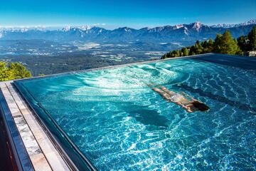 Woman diving in the infinity pool with a view of the mountains, Feuerberg Mountain Resort, Carinthia